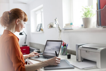 Designer mit Grafiktablett am Laptop im Büro - CAIF09673