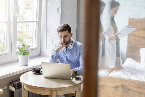 Mann arbeitet an Laptop in Wohnung - CAIF09676