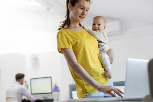 Mutter hält ihre kleine Tochter am Laptop - CAIF09687