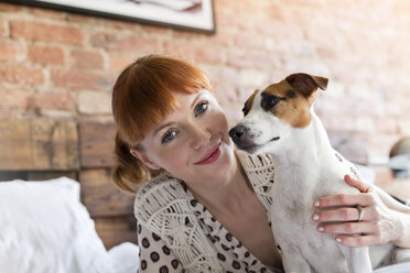 Portrait lächelnde Frau mit Jack Russell Terrier Hund auf Bett - CAIF09698
