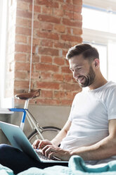 Mann mit Laptop auf dem Bett - CAIF09701