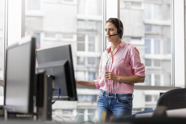 Geschäftsfrau beim Telefonieren mit Freisprecheinrichtung im Büro - CAIF09722