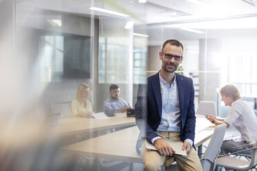 Portrait businessman holding laptop in conference room - CAIF09747