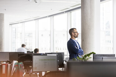 Pensive businessman looking out office window - CAIF09761