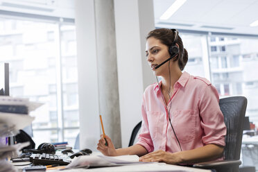 Businesswoman with hands-free device talking on telephone at office desk - CAIF09766