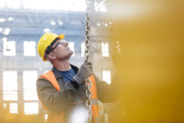 Steel worker holding chain in factory - CAIF09774