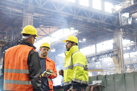 Stahlarbeiter im Gespräch in der Fabrik, lizenzfreies Stockfoto