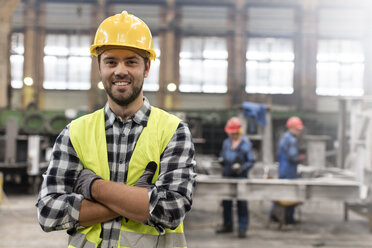 Portrait smiling confident steel worker in factory - CAIF09781