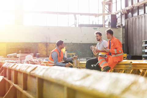 Steel workers enjoying lunch break in factory stock photo