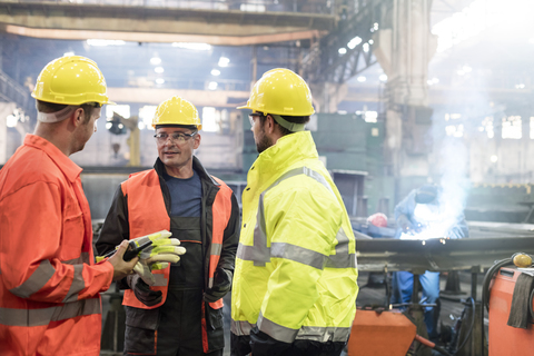 Stahlarbeiter im Gespräch in der Fabrik, lizenzfreies Stockfoto