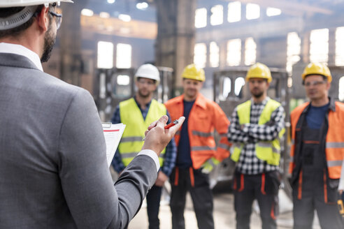 Stahlarbeiter hören dem Manager bei einer Besprechung in der Fabrik zu - CAIF09794