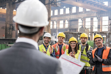 Steel workers clapping for manager in meeting in factory - CAIF09795