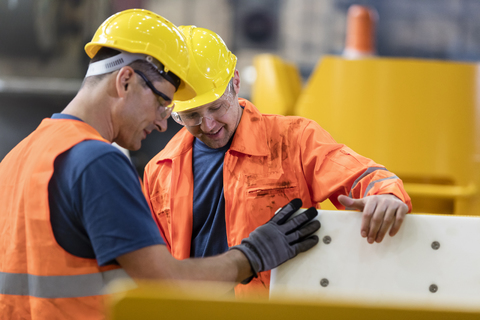 Arbeiter, die einen Teil in der Fabrik untersuchen, lizenzfreies Stockfoto