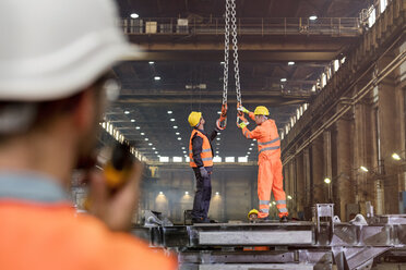 Stahlarbeiter beim Einstellen von Kranhaken in einer Fabrik - CAIF09800
