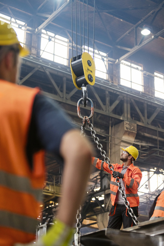 Stahlarbeiter bedienen einen Kran in einer Fabrik, lizenzfreies Stockfoto