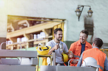 Lächelnde Stahlarbeiter bei der Kaffeepause in der Fabrik - CAIF09811