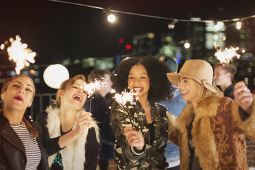 Junge Frauen mit Wunderkerzen auf einer Dachterrassenparty - CAIF09817