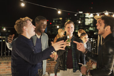 Junge Männer trinken und lachen auf einer Dachterrassenparty - CAIF09823