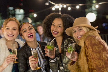 Porträt begeisterter junger Frauen, die auf einer Party Cocktails trinken - CAIF09831