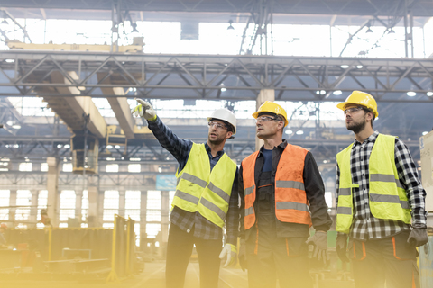 Stahlarbeiter im Gespräch in der Fabrik, lizenzfreies Stockfoto