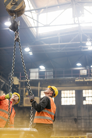 Stahlarbeiter mit Blick auf die Krankette in der Fabrik, lizenzfreies Stockfoto