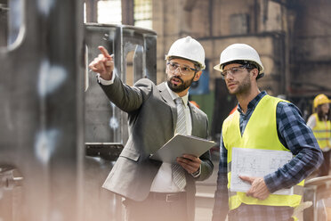 Manager and steel worker talking and looking away in factory - CAIF09851