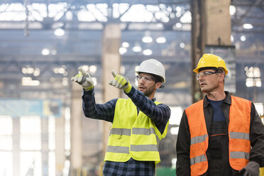 Steel workers talking and pointing in factory - CAIF09859