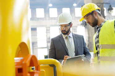 Manager and steel worker examining equipment in factory - CAIF09865