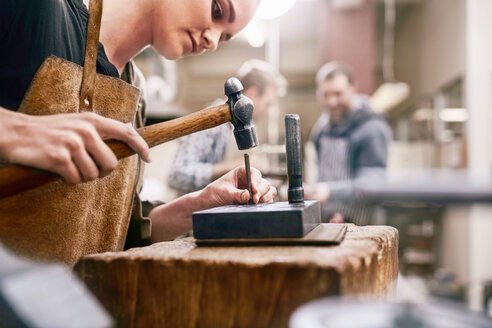 Juwelier mit Hammer in der Werkstatt - CAIF09877