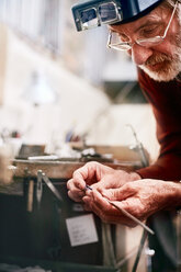 Focused male jeweler working in workshop - CAIF09894