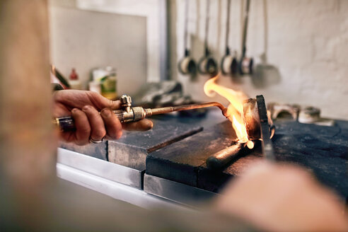 Juwelier erhitzt Metall mit einem Brenner in der Werkstatt - CAIF09899