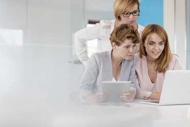 Geschäftsfrauen arbeiten an Laptop und digitalem Tablet in einem Konferenzraum - CAIF09910