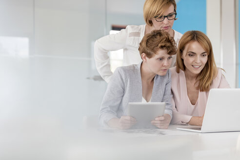 Geschäftsfrauen arbeiten an Laptop und digitalem Tablet in einem Konferenzraum - CAIF09910