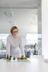 Portrait confident female architect with model in conference room - CAIF09911