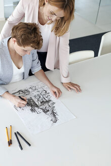 Weibliche Designer zeichnen Skizze im Konferenzraum - CAIF09933