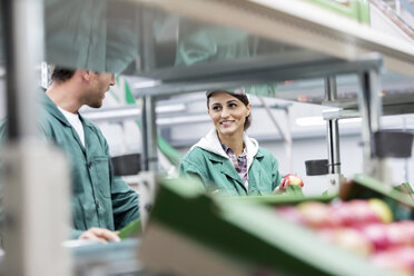 Smiling workers processing apples in food processing plant - CAIF09971