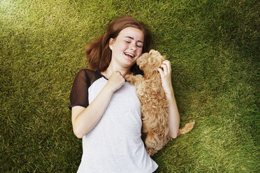 Overhead view happy young woman cuddling affectionate dog in grass - CAIF09989