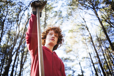 Niedriger Blickwinkel eines Jungen, der eine Gartengabel im Wald hält - CAVF04864