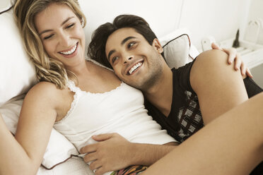 Cheerful couple lying on bed at home - CAVF04887