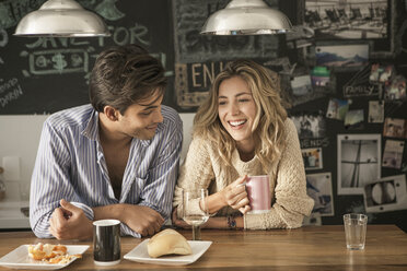 Happy couple sitting at breakfast table in home - CAVF04900