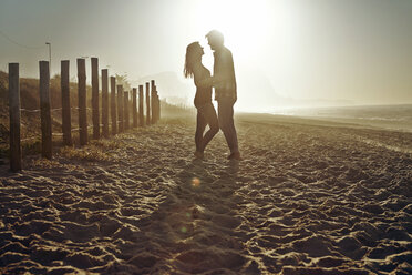 Couple standing on sand against clear sky during sunset - CAVF04914