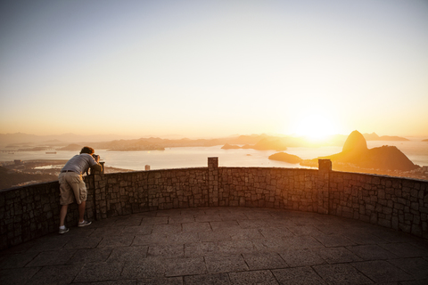 Mann fotografiert den Sugarloaf Mountain, während er bei Sonnenuntergang am Aussichtspunkt steht, lizenzfreies Stockfoto