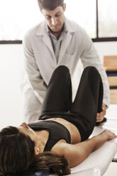 Frau auf dem Bett liegend, während der Arzt sie im Krankenhaus untersucht - CAVF04948