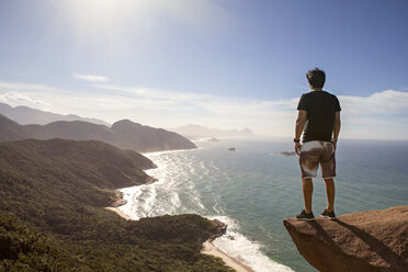 Rear view of hiker standing cliff by sea - CAVF04992