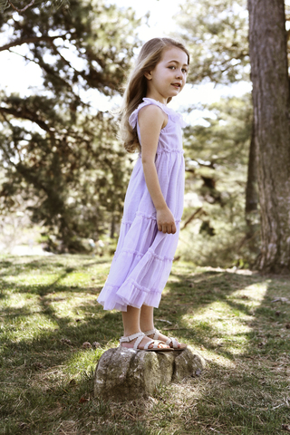 Glückliches Mädchen steht auf einem Felsen im Hinterhof, lizenzfreies Stockfoto