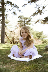 Porträt eines glücklichen Mädchens, das auf einer Decke im Hinterhof sitzt - CAVF05017