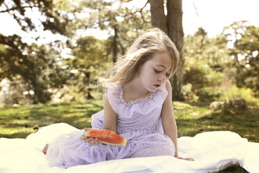 Mädchen mit Wassermelone auf einer Decke im Hinterhof sitzend - CAVF05021