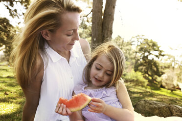 Mutter betrachtet Mädchen mit Wassermelone im Hinterhof - CAVF05024