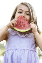 Porträt eines Mädchens, das im Hinterhof eine Wassermelone gegen den Himmel isst - CAVF05026