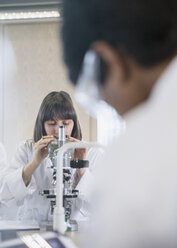 Studentin mit Mikroskop bei der Durchführung eines wissenschaftlichen Experiments in einem wissenschaftlichen Labor - CAIF09996